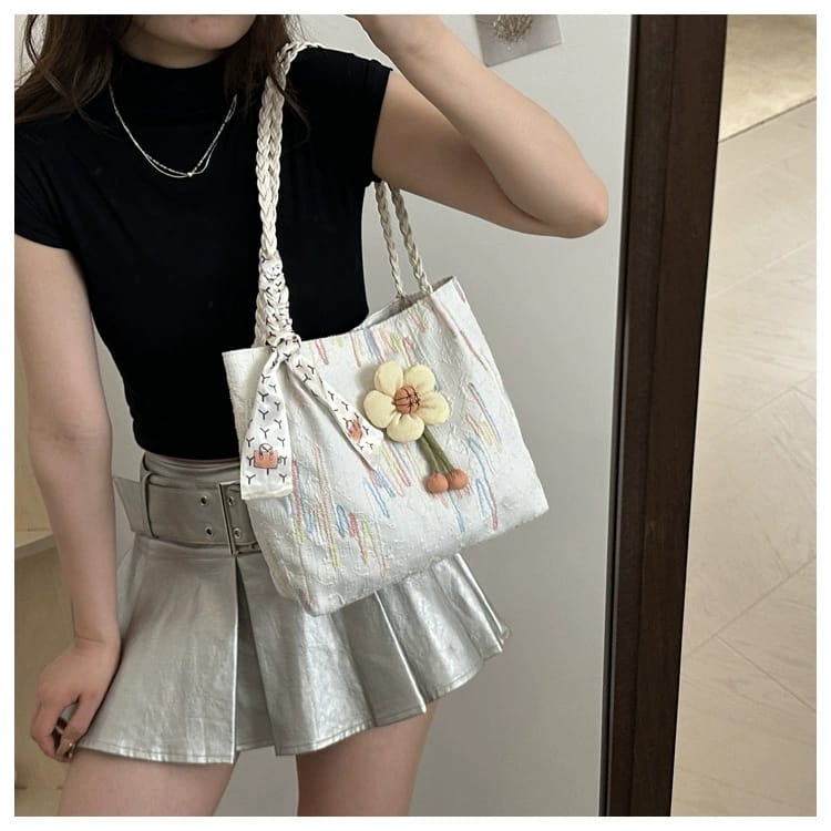 Woman in a black top and silver skirt carrying a TRENDBUY white floral charm tote bag