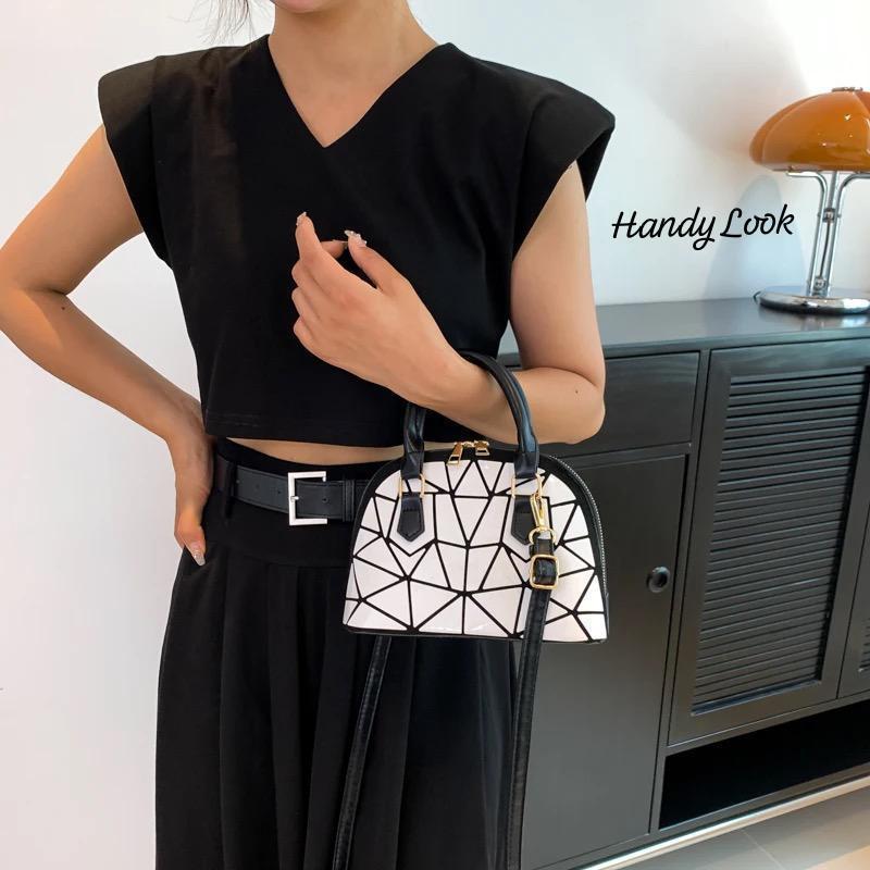 TRENDBUY geometric Bao Bao dome handbag in white, carried by hand by a woman in black for a handy look