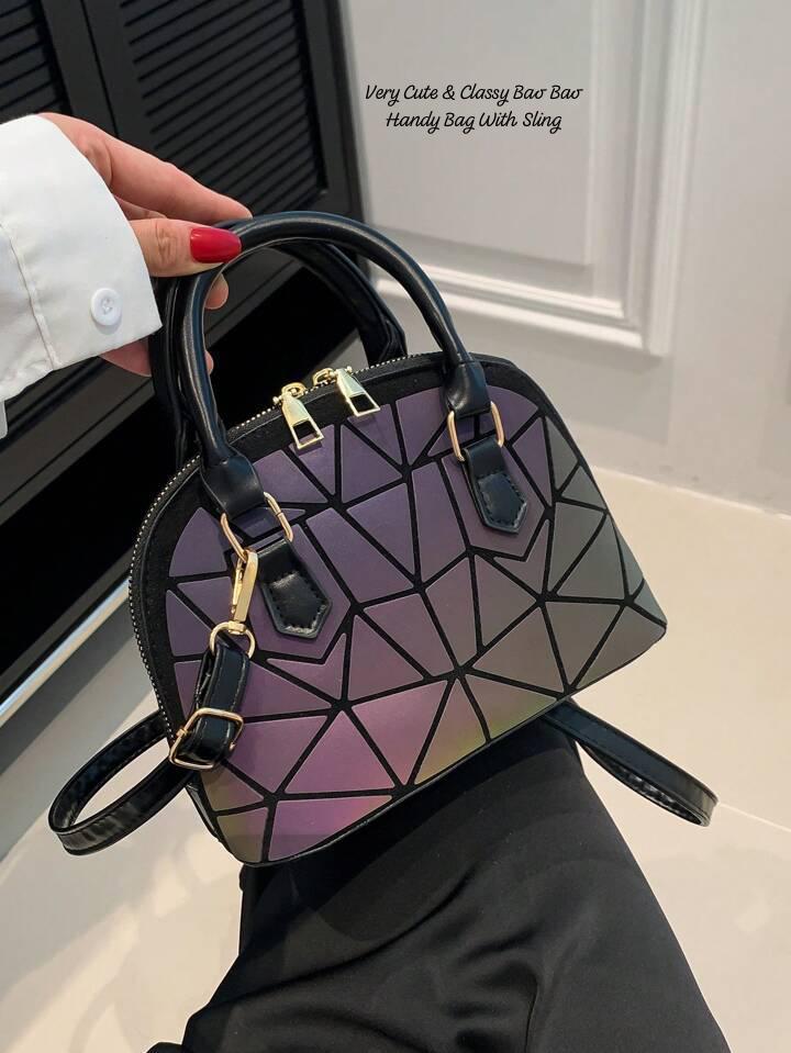 Close-up of an iridescent geometric Bao Bao dome handbag with black trim and sling, held by hand, showcasing its unique color-shifting design