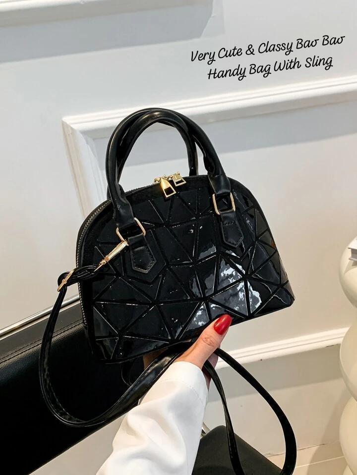 Close-up of a glossy black geometric Bao Bao mini handbag with black trim and sling, held by hand, highlighting its sleek and classy appearance