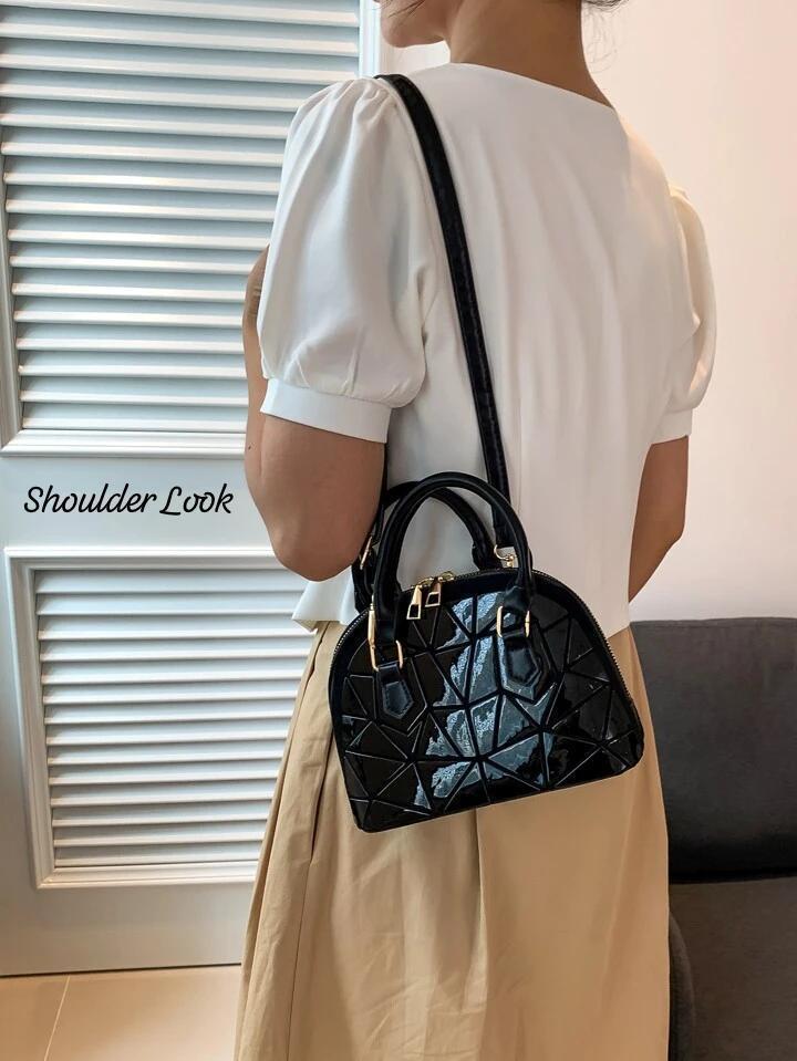 Woman wearing a glossy black geometric Bao Bao dome handbag on her shoulder, paired with a white top and skirt, demonstrating a stylish shoulder look