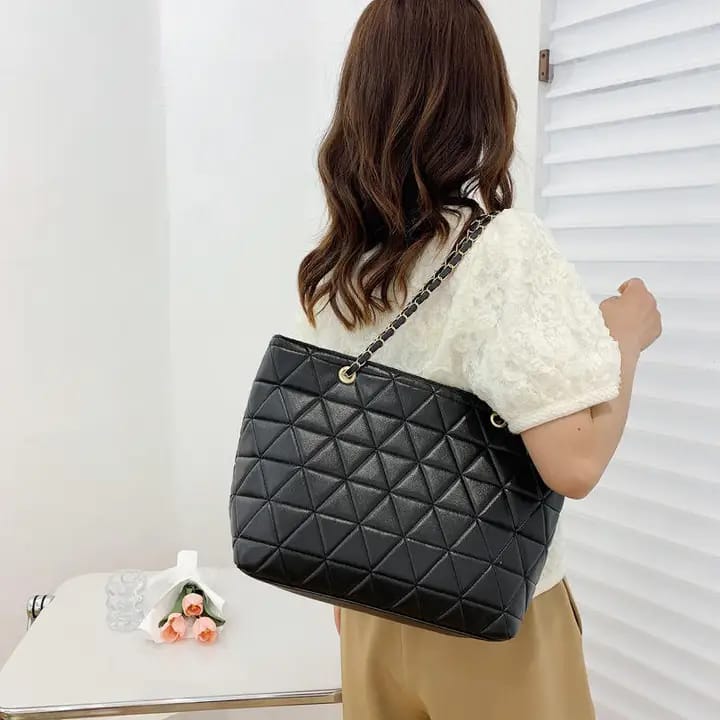 TRENDBUY elegant black rhombus quilted tote bag with golden chain straps, carried by a woman
