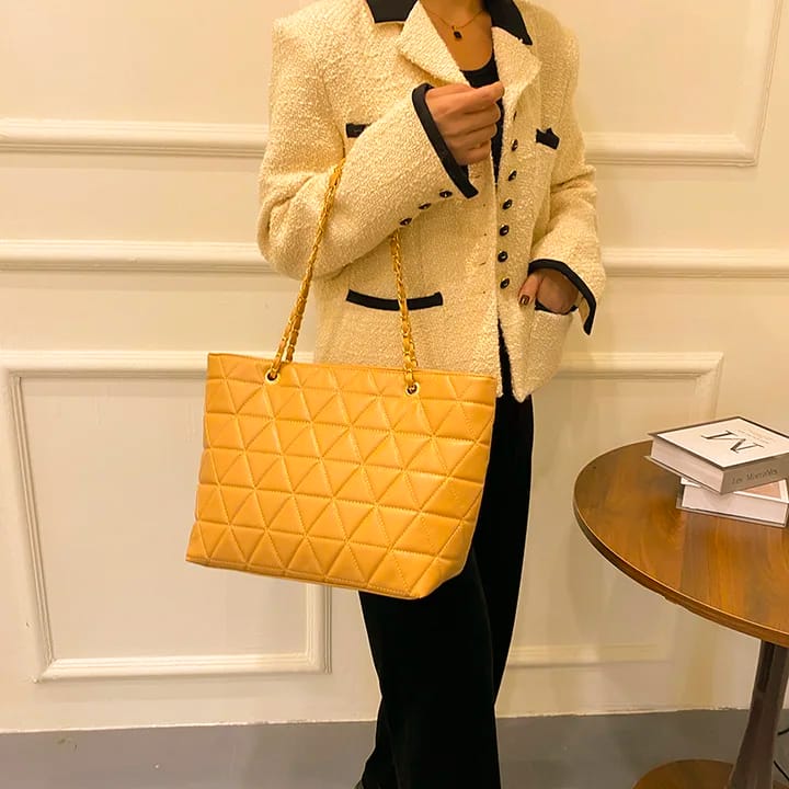 Woman carrying a TRENDBUY stylish mustard yellow rhombus quilted tote bag with golden chain straps