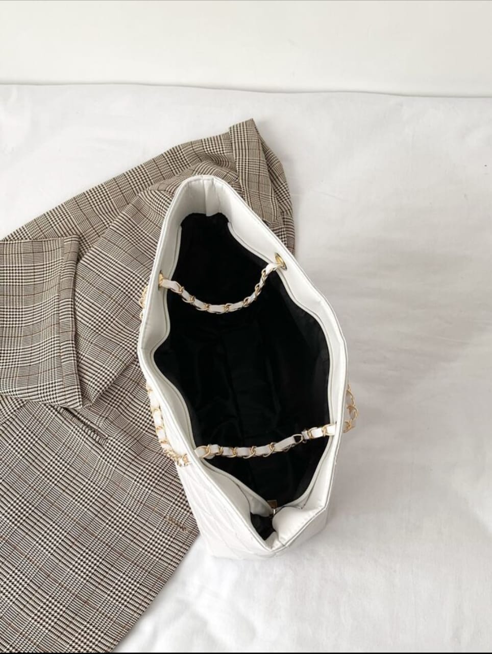 Top-down view of the spacious interior of a TRENDBUY white rhombus quilted tote bag, showing black lining and chain details