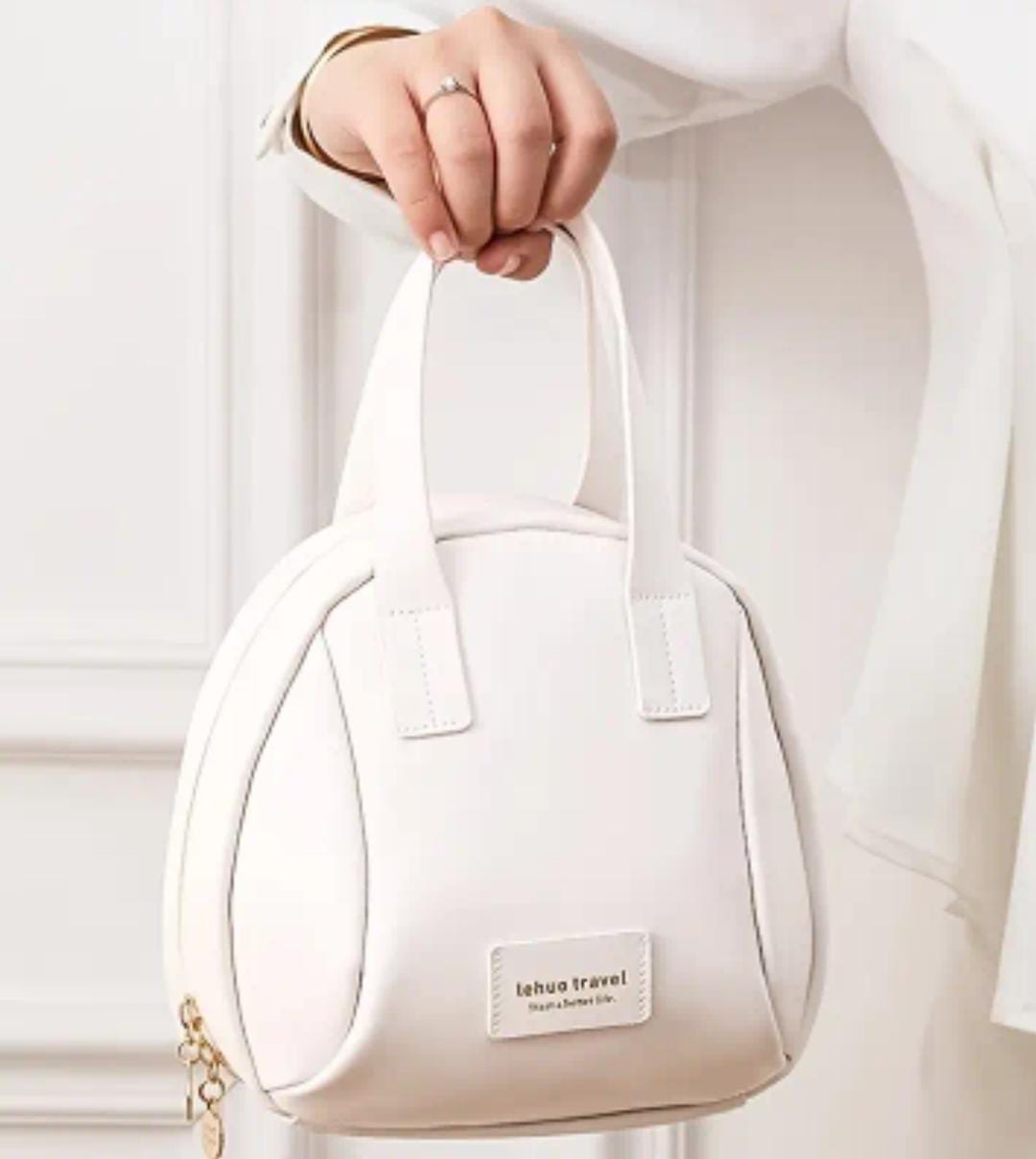 A hand holding up a white 'lehuo travel' branded large capacity cosmetic bag by its top handle, emphasizing portability.