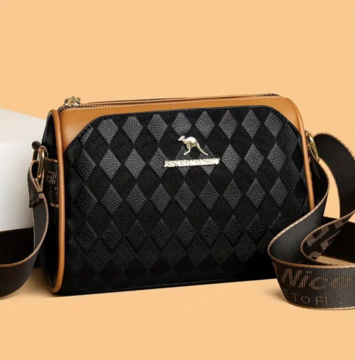 TRENDBUY women's geometric Boston sling bag in black with gold kangaroo logo and patterned strap. Front view.