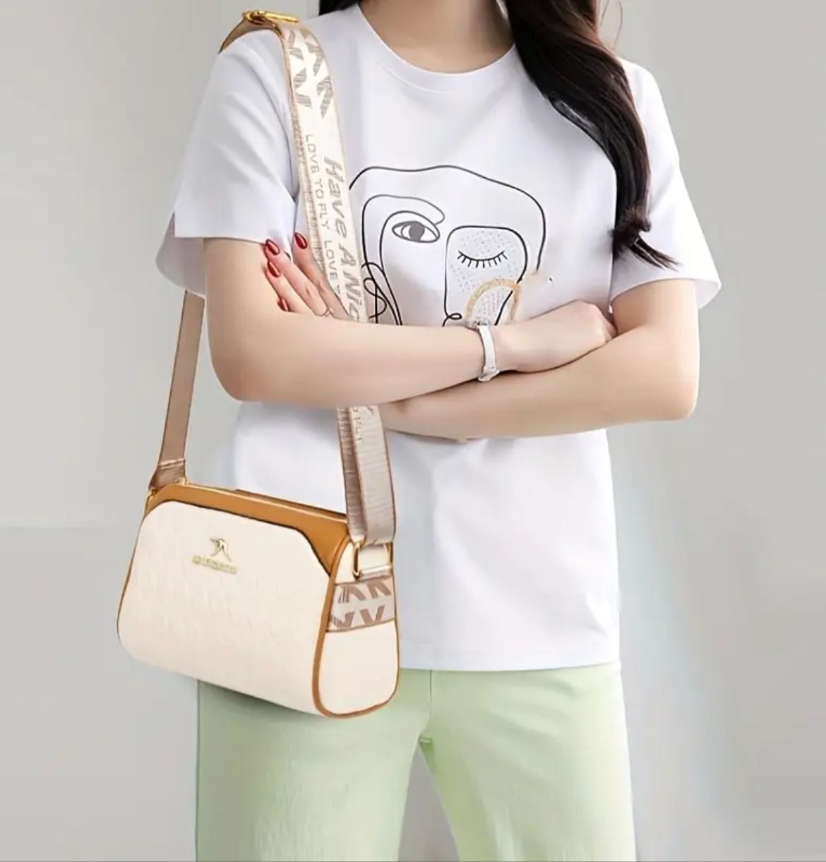 Model showcasing TRENDBUY cream geometric sling bag worn as a crossbody with a white t-shirt and light green pants.