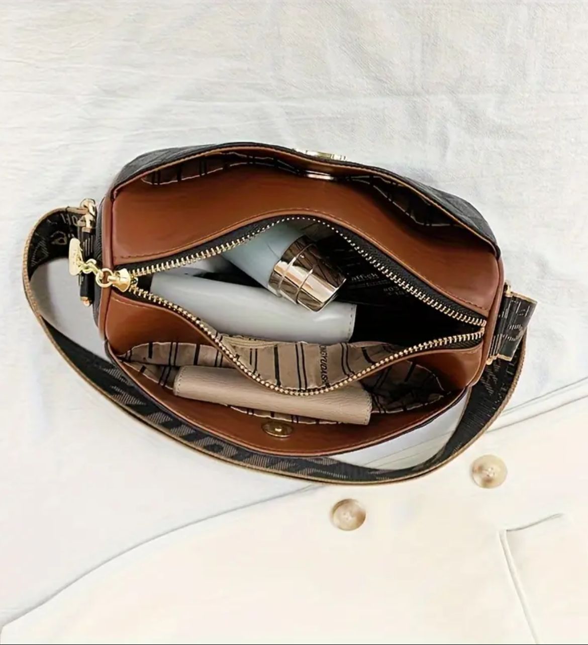 Overhead view of the interior of TRENDBUY black geometric sling bag with personal items organized inside.