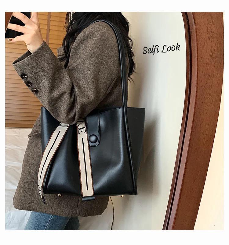Stylish woman carrying the TRENDBUY black PU leather tote bag with a 'LOVE' strap, reflected in a mirror.