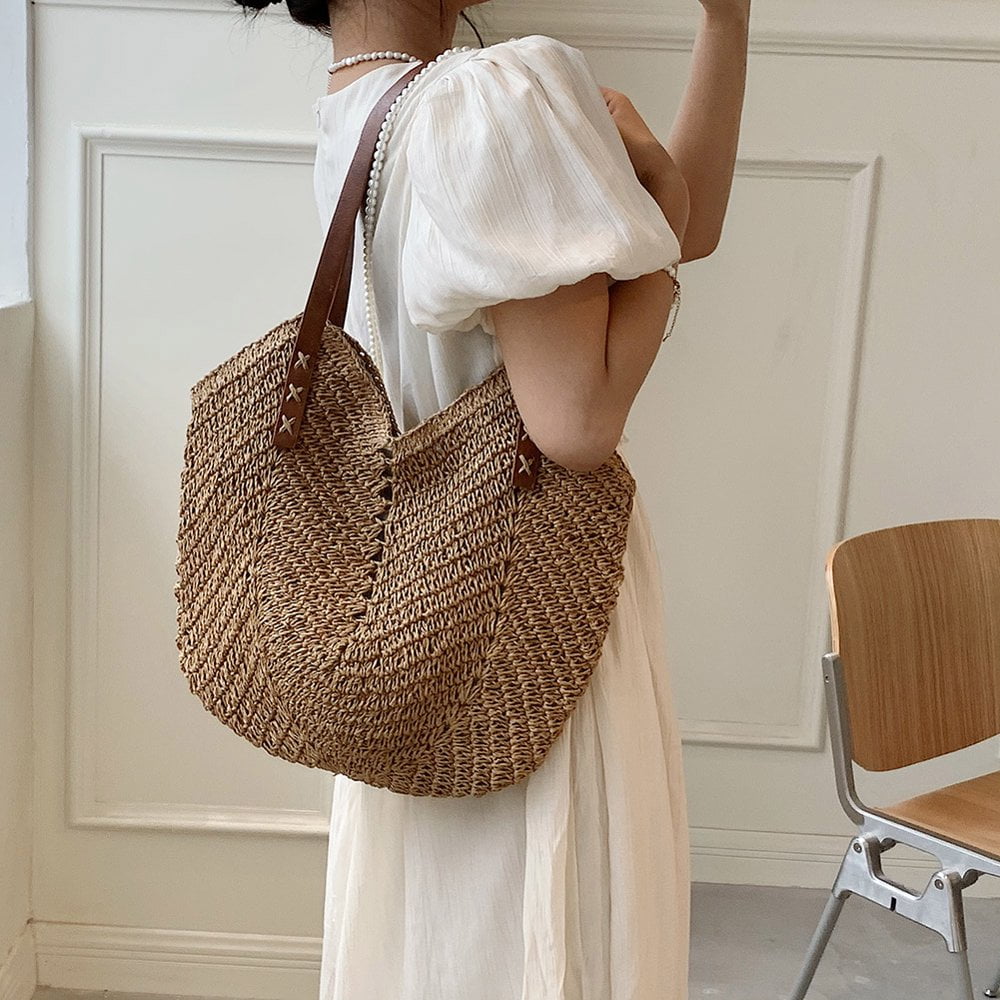 Woman in a flowing white dress carrying a natural brown TRENDBUY woven tote bag, showcasing its generous size and casual chic style.