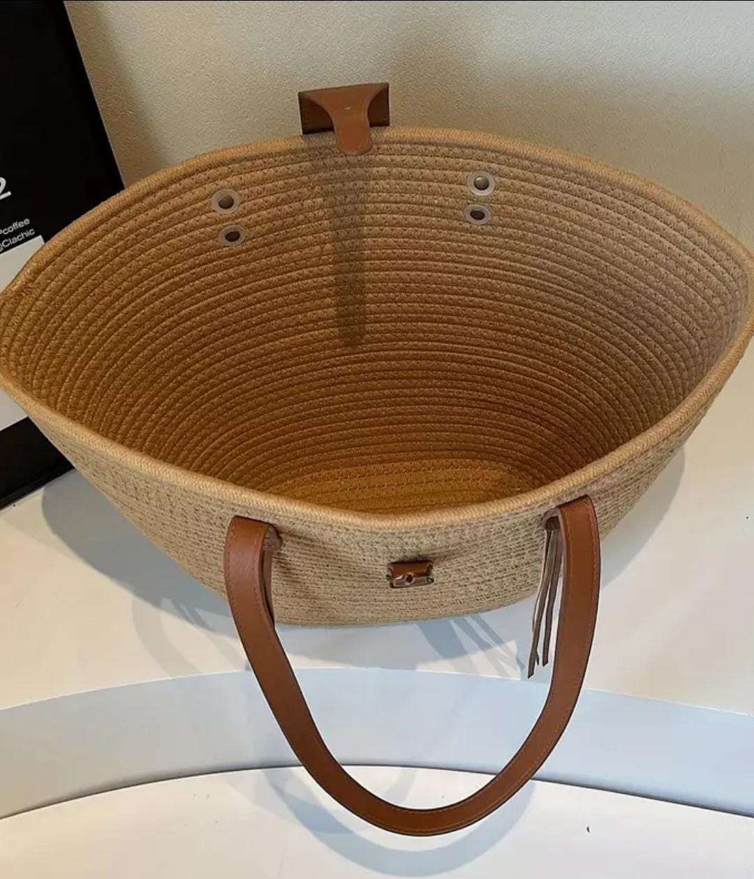 Overhead view inside the empty main compartment of the TRENDBUY beige straw tote bag, showing its woven texture.