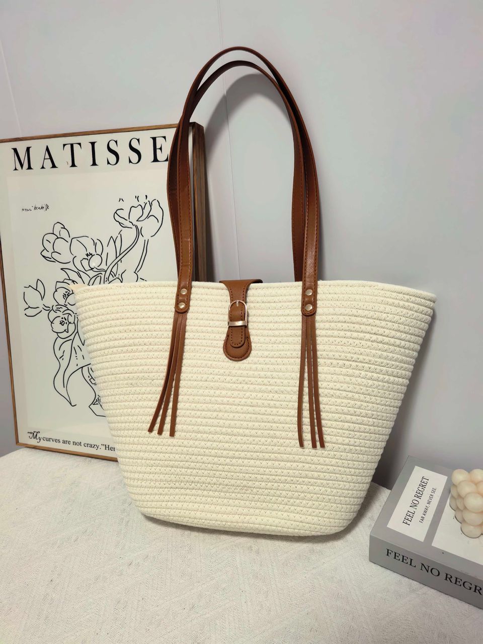 TRENDBUY white straw weave tote bag on a textured surface, art print in background, showcasing its crisp color.