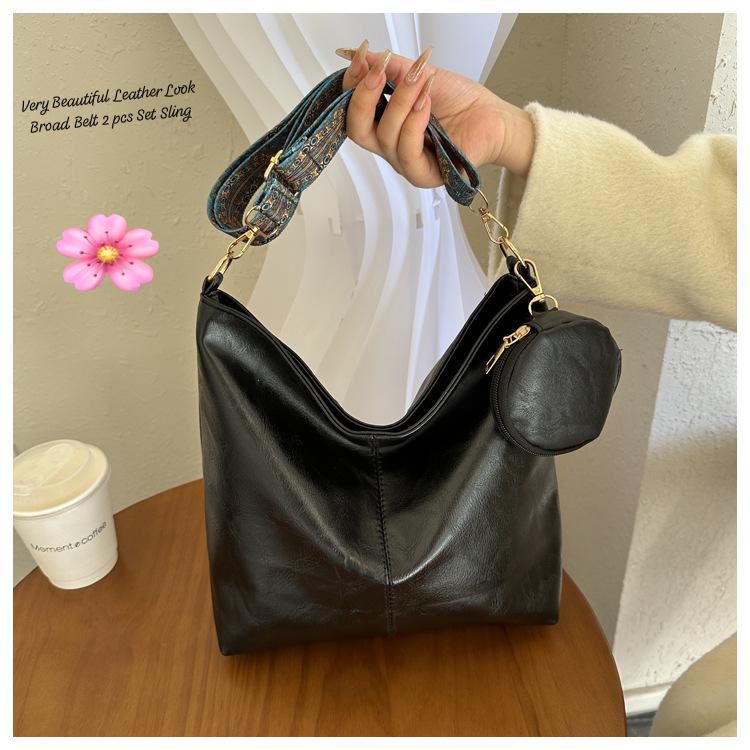 Black TRENDBUY PU leather tote bag with a matching small coin pouch attached to the handle, held by a hand on a wooden table.