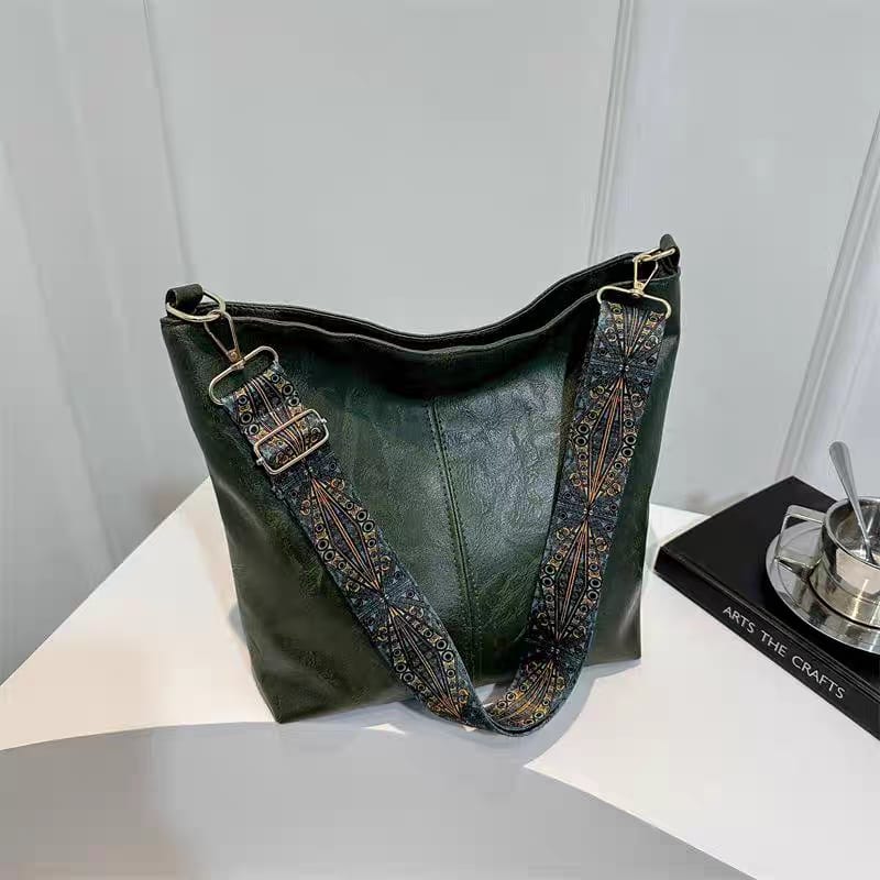 Another view of the dark green TRENDBUY PU leather tote bag with its patterned strap, styled on a white table with minimalist decor.