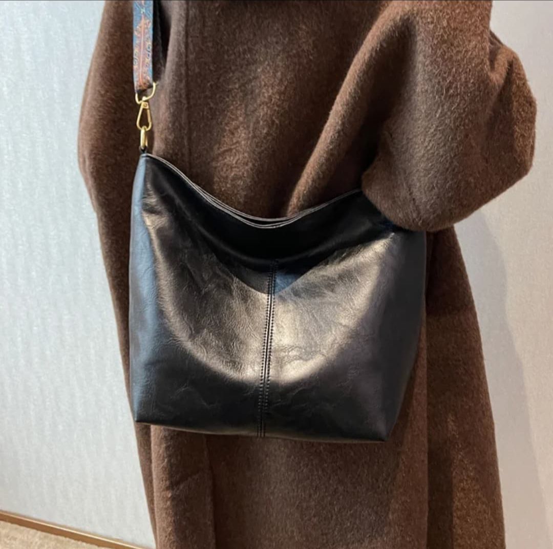 Model in a brown textured coat carrying a black TRENDBUY PU leather tote bag over her shoulder, captured indoors.