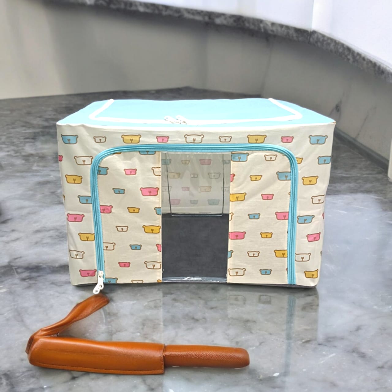 Cream storage box with colorful bear patterns, light blue top, blue zippers, isolated shot of the storage box.