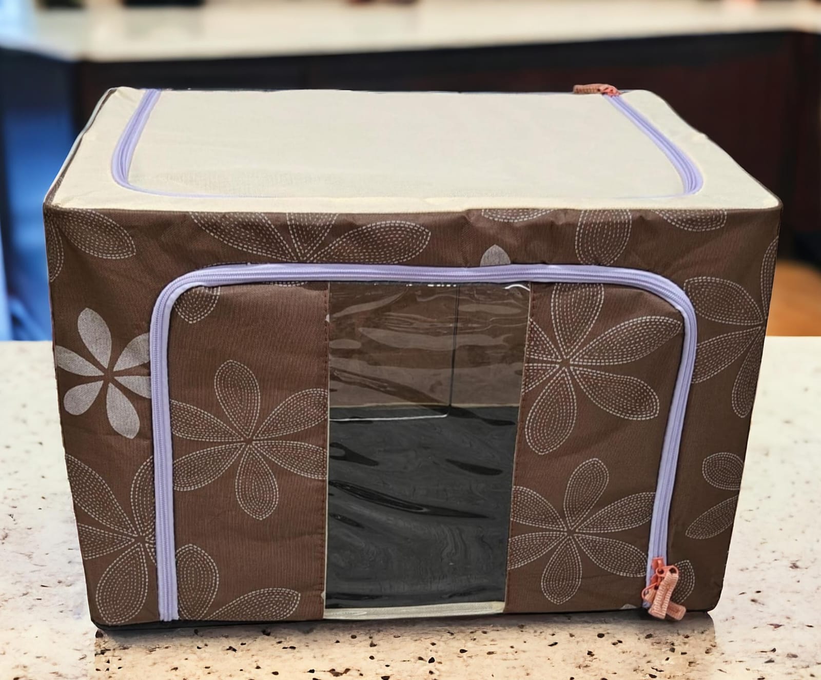 Brown floral patterned fabric storage box with light purple zippers and red pulls, interior visible through window.