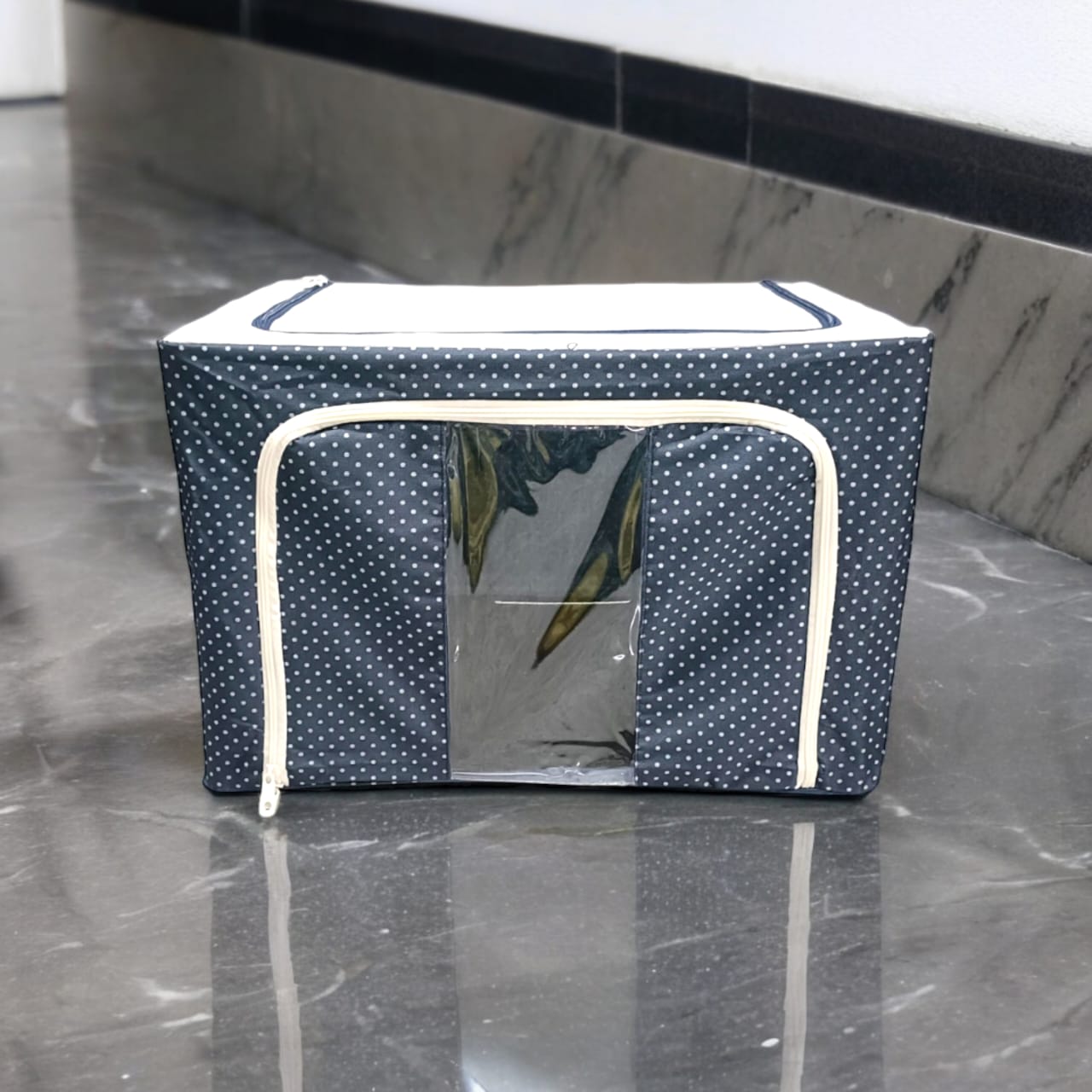 Dark blue polka dot fabric storage box with white zippers, presented on a clean, reflective surface.
