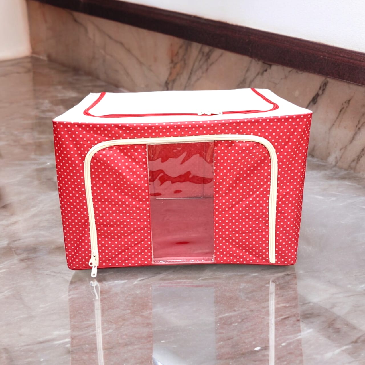 Red polka dot fabric storage box with white zippers, on a polished floor, emphasizing clean lines.