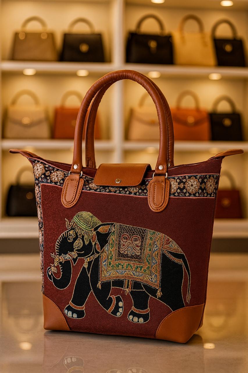 TRENDBUY maroon canvas tote bag showcasing a majestic black elephant with intricate gold and green embroidery, complemented by brown leather handles.