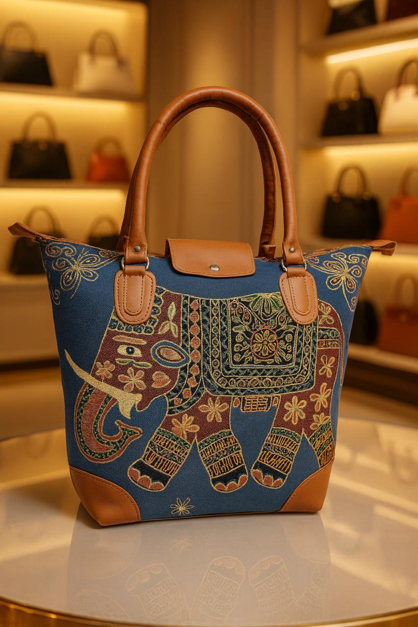 TRENDBUY deep blue canvas tote bag adorned with a vibrant, embroidered elephant pattern, featuring floral and geometric designs, complete with brown leather handles.