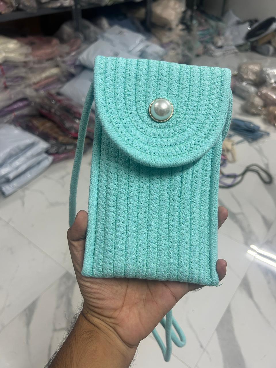 Aqua blue braided crossbody phone bag with pearl button flap closure, held in hand.