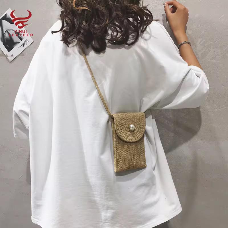 Model wearing a beige braided mini phone bag crossbody style over a white t-shirt.