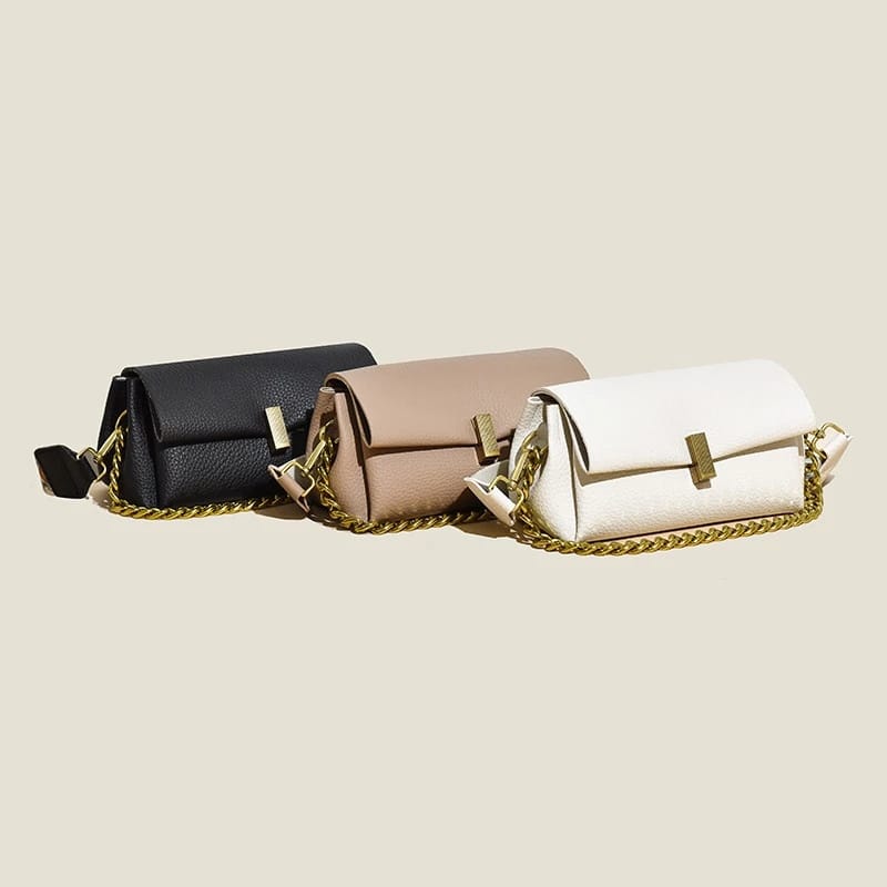 Three TRENDBUY sling bags in black, beige, and white, showcasing broad patterned straps and elegant chain details.