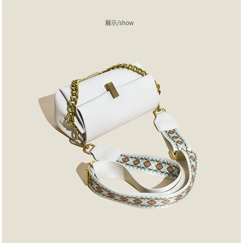 Angled shot of the white TRENDBUY sling bag, emphasizing its textured PU leather and the intricate pattern of the broad shoulder strap.