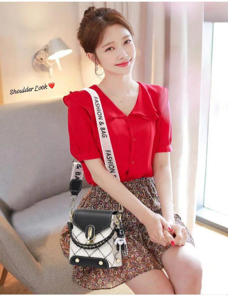 Woman in a red blouse and a floral skirt, smiling while wearing the TRENDBUY black and white broad belt sling bag as a shoulder bag.