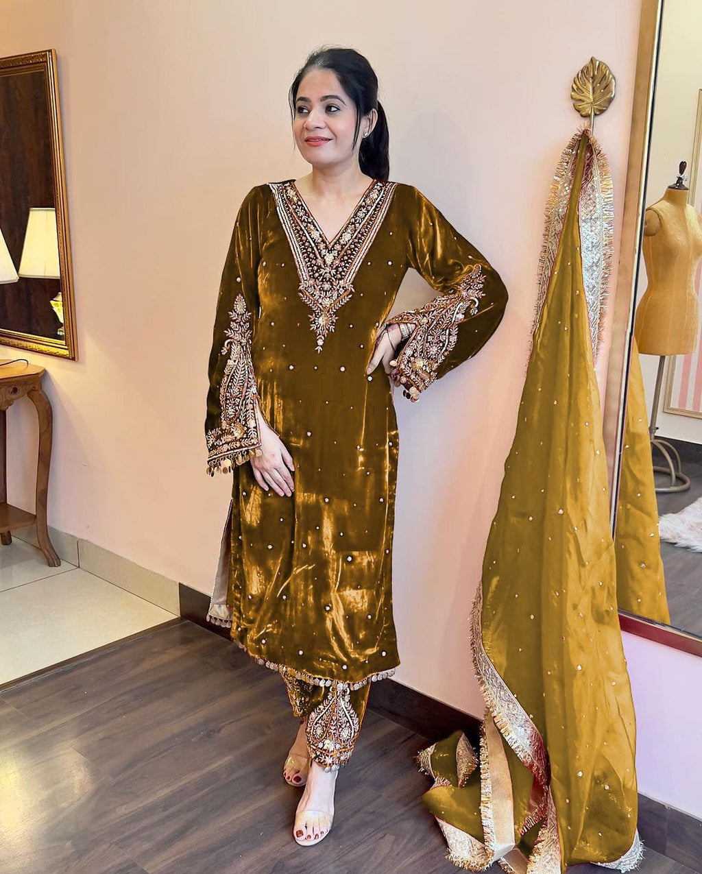 Yellow Pakistani velvet suit with intricate embroidery, worn by a woman.
