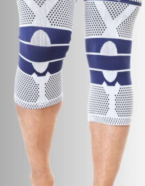 Black adjustable 4-way compression knee support worn on a knee.