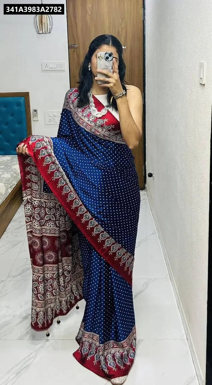 Model showcasing TRENDBUY Ajrakh Modal Silk Saree in classic blue with white dotted body and traditional red printed border, standing pose.
