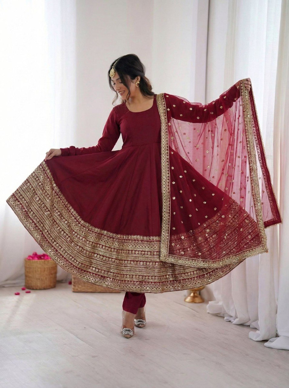 Model in a maroon Roman silk Anarkali gown with golden sequence work, twirling gracefully.