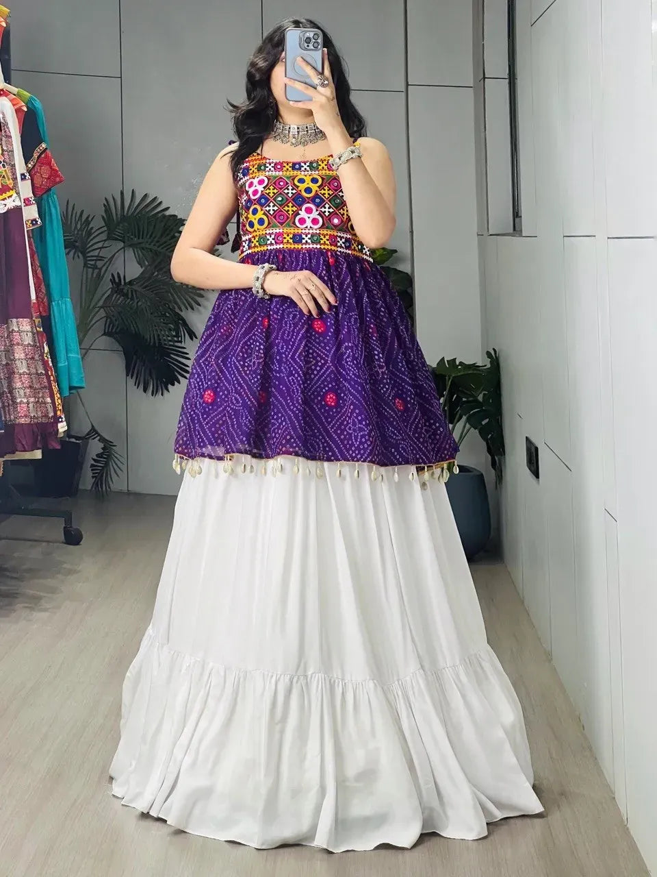 Model posing in purple Bandhani Kediya top paired with a white flared tiered cotton lehenga