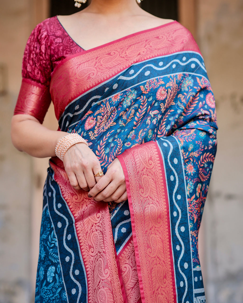 Close-up of a woman's hands and mid-section showing the detailed digital print floral design and ornate zari border of the Banarasi silk saree.