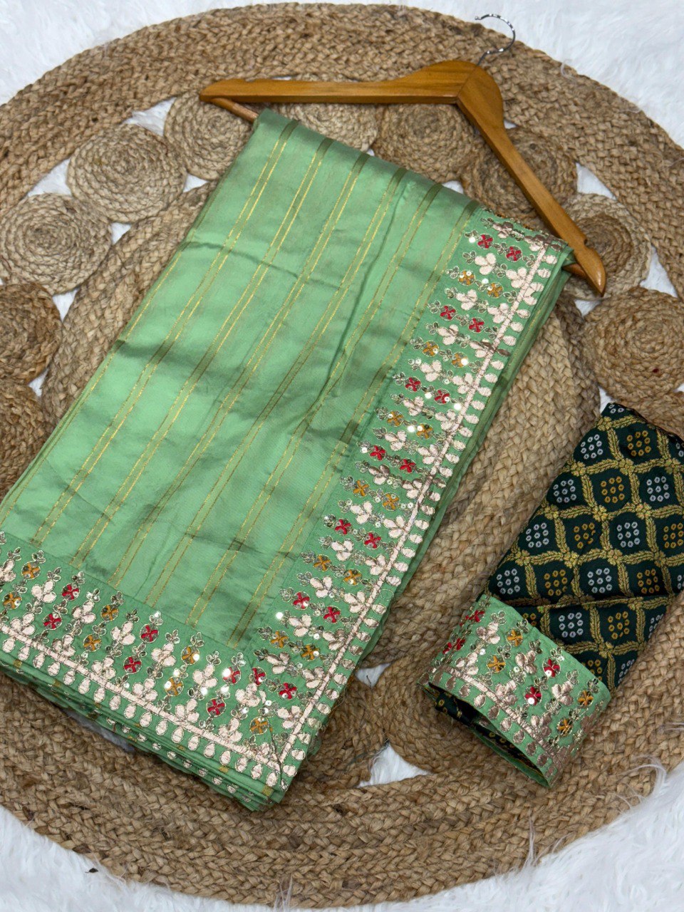 TRENDBUY Banarasi Silk Saree with zari weaving and sequin border, draped with brocade blouse fabric on a jute mat.