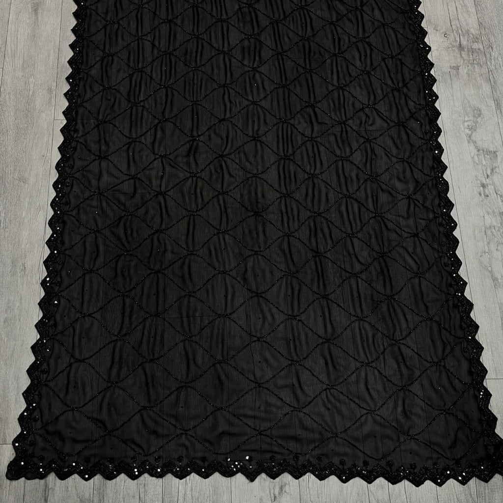 Close-up of black georgette saree fabric with intricate black beads and sequence work.