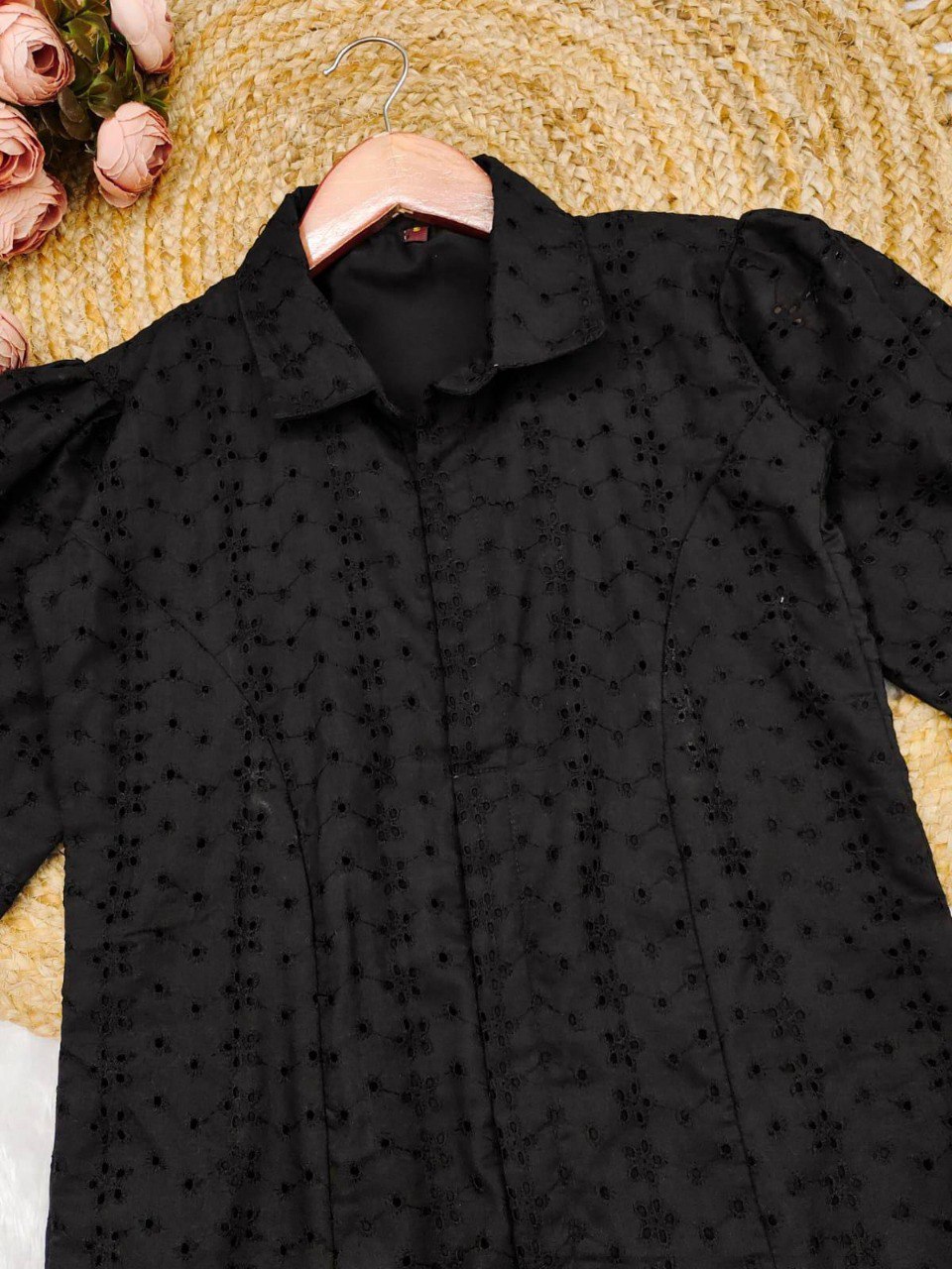 Close-up of intricate Schiffli embroidery and delicate eyelet cutouts on black cotton fabric