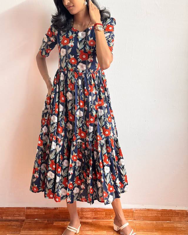 Woman posing elegantly in a TRENDBUY Blue Floral Print Tiered Short Frock Dress, showcasing its vibrant design.