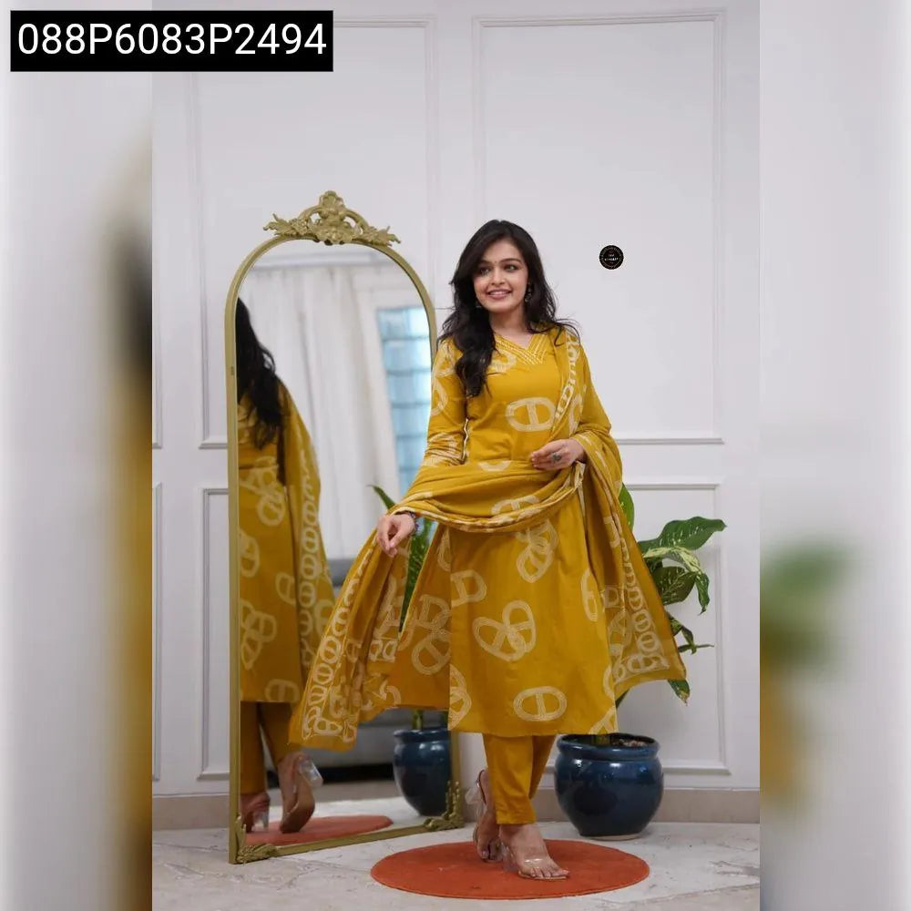 A smiling woman wearing a mustard yellow Chanderi Cotton embroidered kurti set with matching pants and dupatta, standing in front of a mirror.