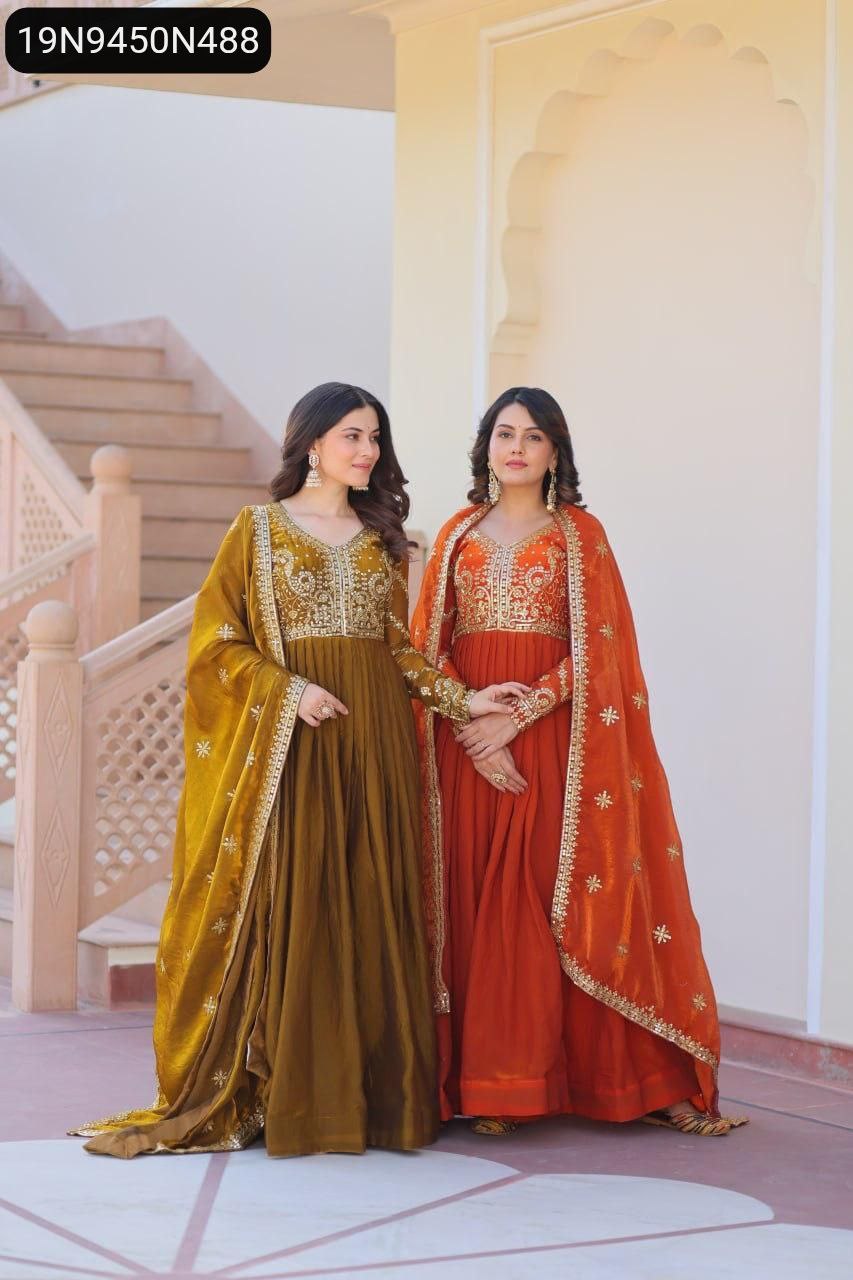 Two women posing in elegant Fendy Fabric Gowns with Zari Sequins Embroidered Dupattas – one in rich Fenta (brownish-gold) and one in vibrant Mehendi (rust/orange).