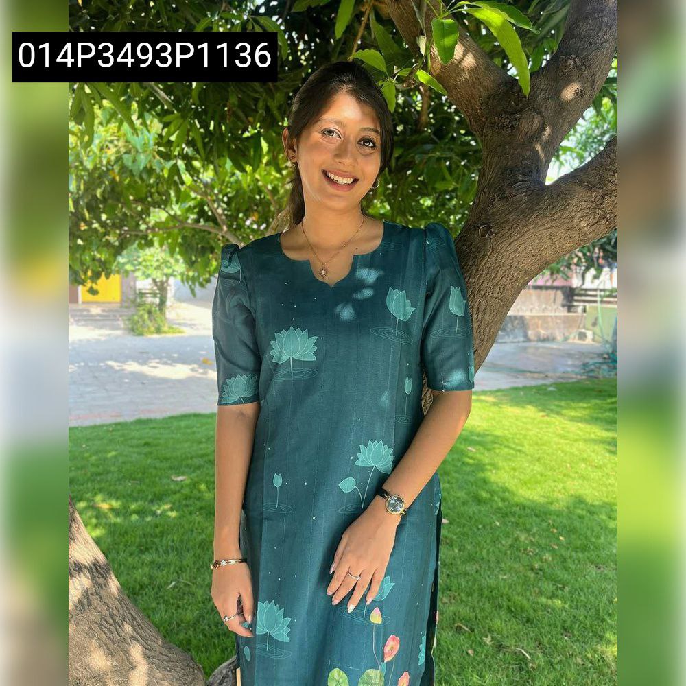 Woman smiling, wearing a dark teal printed pure cotton kurti with a V-neck and lotus motifs, standing outdoors.