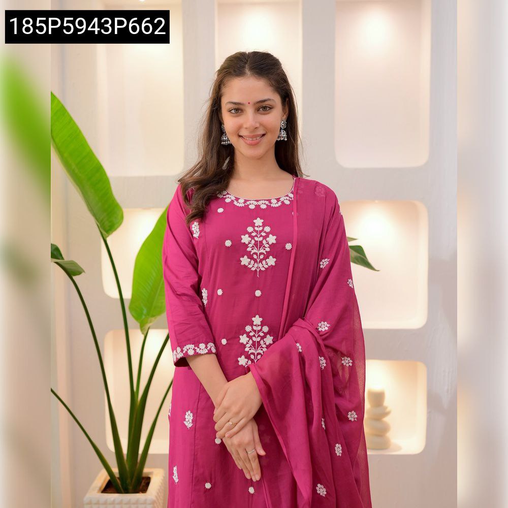 Smiling woman posing in a magenta Roman silk embroidered suit set with white floral embroidery and matching dupatta.