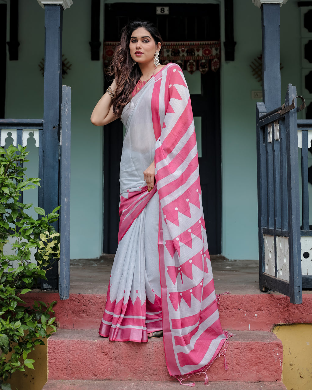 Elegant woman posing in a Chic White and Pink Linen Saree with Chevron and Polka Dot patterns, perfect for festive occasions.