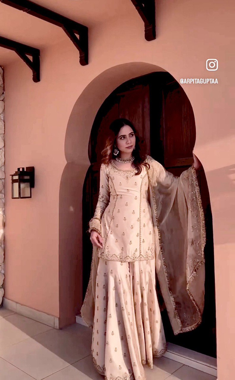 Model posing in a radiant Champagne Beige Cinon embroidered sarara set with sequence work, perfect for festive occasions.