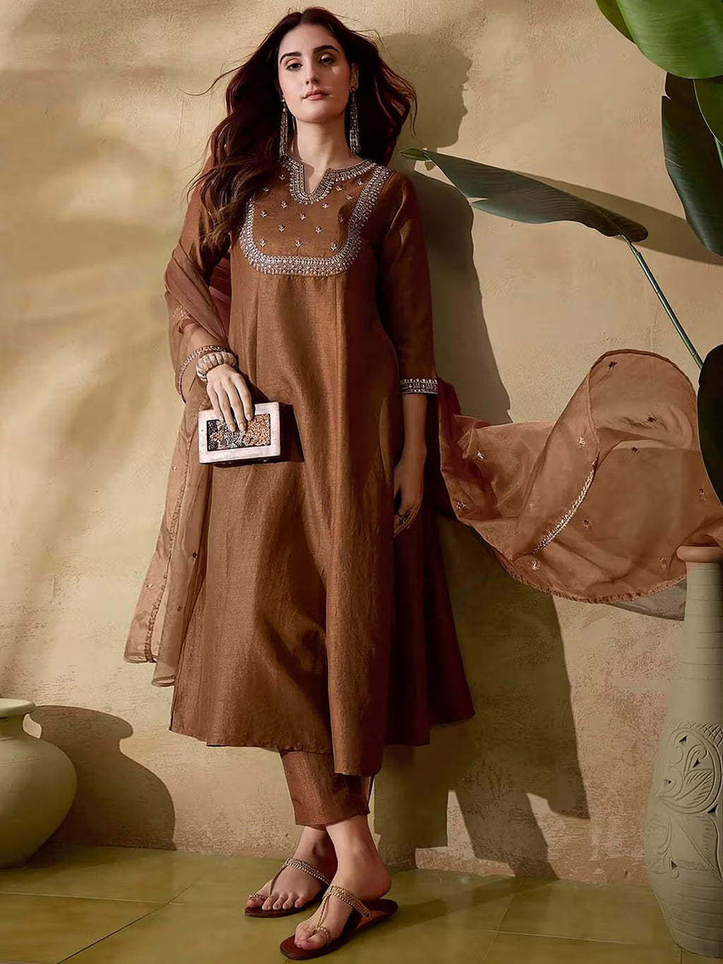 Woman posing in elegant brown Vichitra silk kurta set with embroidered neckline and sheer dupatta.