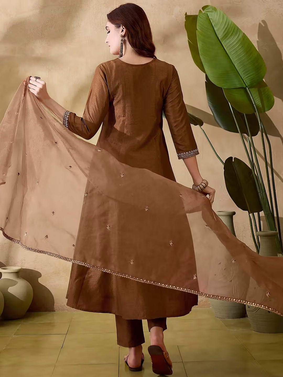 Woman seated gracefully in a brown Vichitra silk kurta set, highlighting the intricate embroidery and luxurious fabric.
