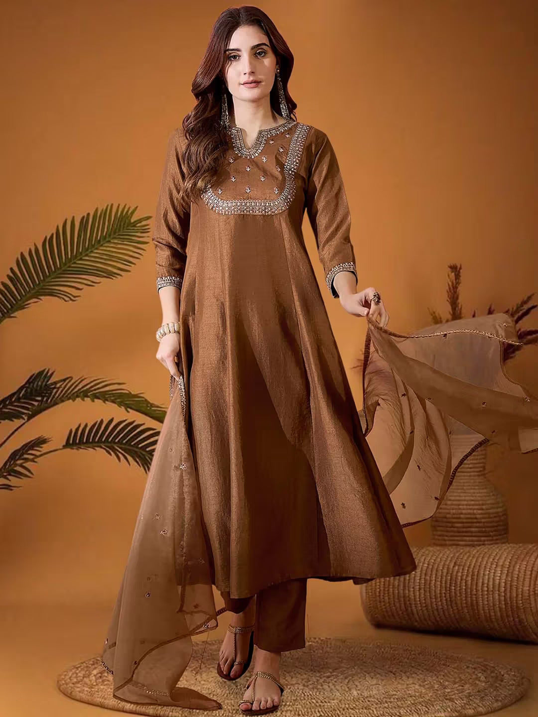 Woman in brown embroidered Vichitra silk kurta pant dupatta set against a warm backdrop, emphasizing the rich color and craftsmanship.