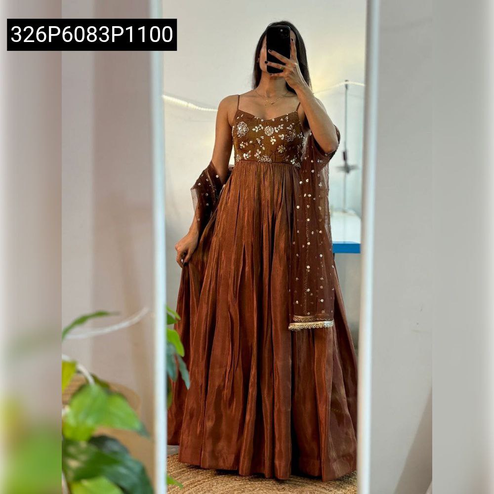 Full body shot of model wearing an Earthen Brown embroidered Cosmos suit set with matching dupatta, holding a phone.